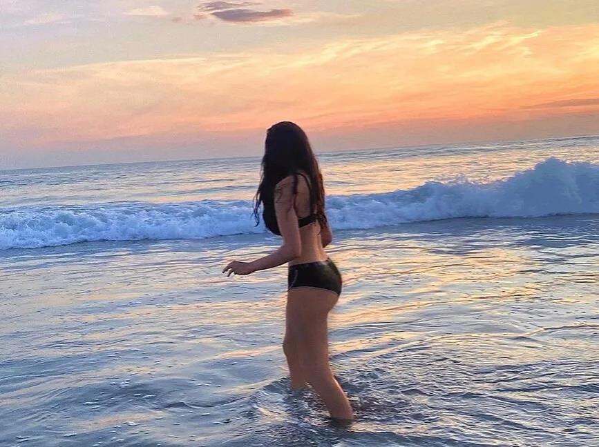 А тут она снова на фоне морской волны в чёрном купальнике.